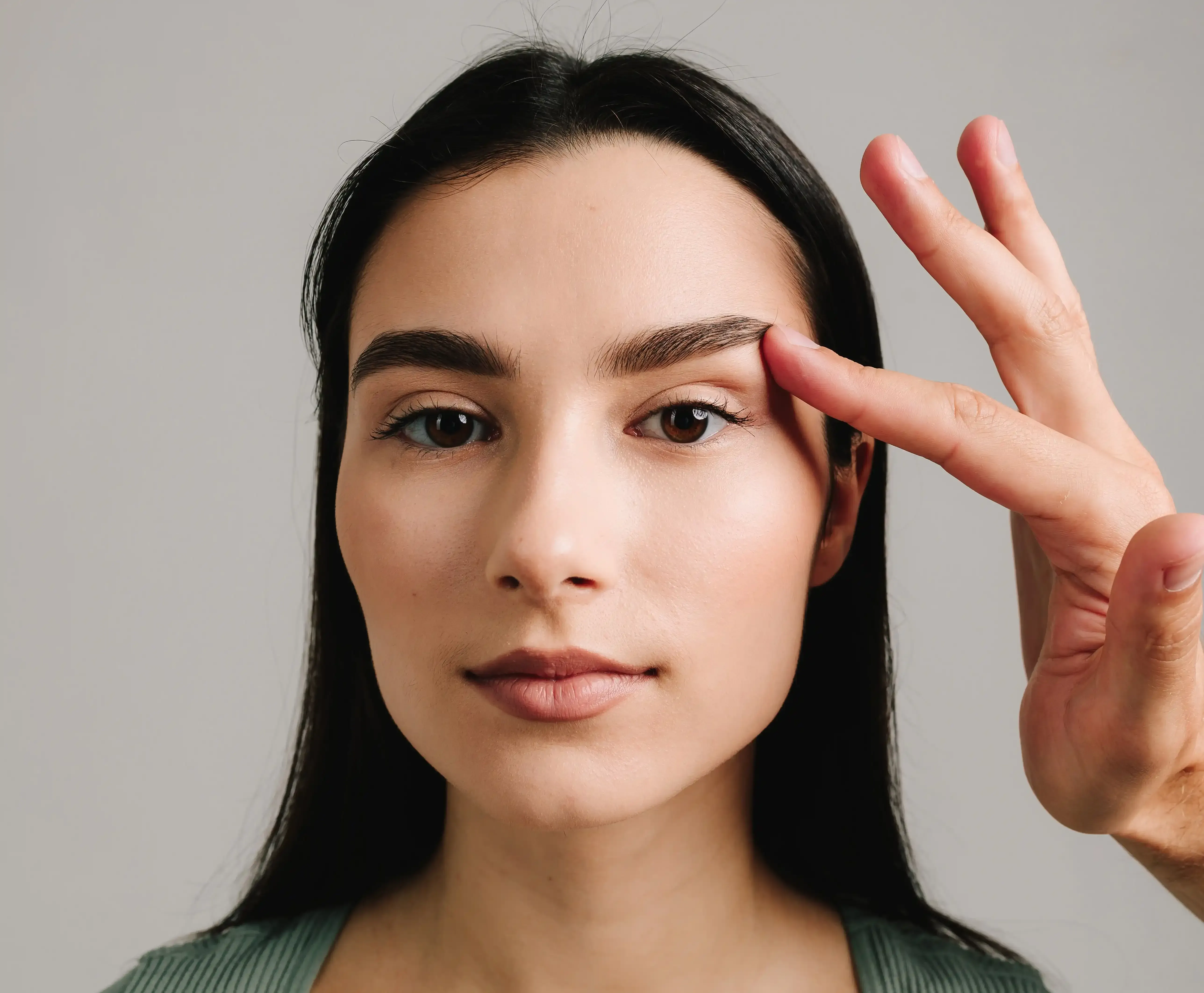 Woman examining her droopy upper eyelids in a mirror at Healthy Enhancements Wellington